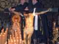 Imagen religiosa de un Cristo crucificado en una iglesia, rodeado de velas y decoraciones ornamentales.