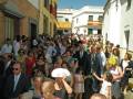 Una multitud de personas en una calle, con una bandera española en el fondo. La escena parece ser una celebración o una reunión pública.