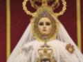 Imagen de la Virgen María con el Niño Jesús, vestida con trajes tradicionales dorados y adornos religiosos.