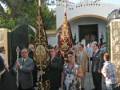 Procesión religiosa con estandartes y personas participando en una celebración en una localidad española.