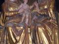 Escultura gótica de la Virgen con el Niño y Santa Ana, dorada y detallada, en un entorno religioso.
