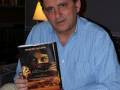 Persona sosteniendo el libro "Ultima Promesa" de Alejandro Zabala, en un ambiente acogedor con luces cálidas.