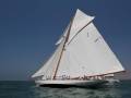 Barco clásico blanco navegando en el mar, con una vela grande y un asta de madera.