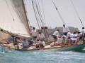 Barco de vela clásico navegando en el mar con una torre en el fondo.