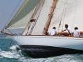 Barco de vela clásico navegando en el mar, con dos personas a bordo.