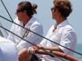 Dos hombres en camisas blancas disfrutan de un día de vela bajo el sol.