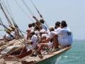 Equipo español en competencia de vela, navegando con entusiasmo bajo un cielo azul.