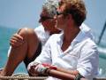 Dos personas en una embarcación, uno con guantes de seguridad y el otro con gafas de sol, disfrutando de la vista del mar.
