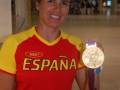 Una atleta española posa con una medalla dorada en un aeropuerto.