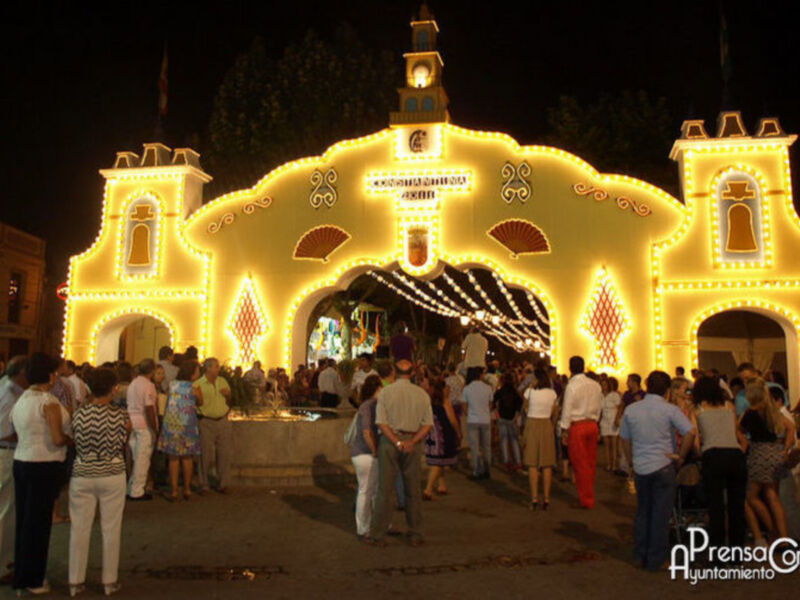 Fiesta en la plaza de la iglesia iluminada con luces festivas y gente disfrutando de la noche.