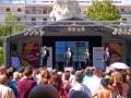 Ecuador en Sevilla, evento cultural con tres presentadores en escenario. Público asistente disfrutando del evento.