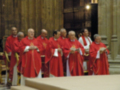 Misa religiosa en una catedral con sacerdotes vestidos de rojo.
