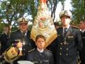 Un grupo de marineros en uniforme celebran una ceremonia, con un joven en el centro y dos adultos a su lado. La imagen muestra detalles de la vestimenta naval, incluyendo insignias y sombreros. La escena parece ser parte de una celebración o ceremonia naval, posiblemente en honor a un evento importante.