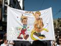 Una pancarta con una caricatura de un hombre en traje y otro en traje de marinero, sosteniendo una escoba.