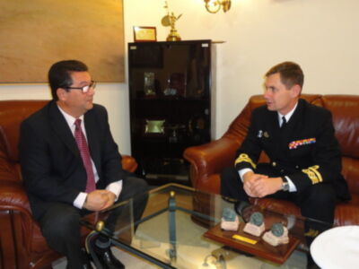 Entrevista entre un diplomático y un oficial naval en un ambiente formal.