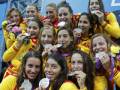 Una selección femenina de fútbol celebrando con medallas y flores.