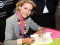 Una mujer sonriente firma un libro en una presentación de la Fundación Cofares.