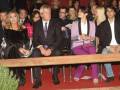 Una imagen de una gala o evento formal con personas sentadas en filas. La gente está vestida con trajes y chaquetas, algunos con corbatas. En el fondo hay luces y un escenario. La imagen parece ser de una celebración o premiación.