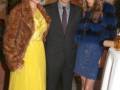 Una celebración formal con tres personas posando juntas, dos de ellas vestidas con vestidos brillantes y la tercera con un traje formal.