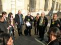 Un grupo de personas se reúne en una plaza histórica, posiblemente para una visita guiada o una reunión formal.