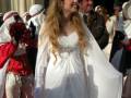 Una mujer con vestido blanco y tocado de plumas, posando en un escenario formal.
