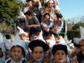 Una imagen de una escena festiva con personas vestidas con disfraces y sombreros blancos, posiblemente en un evento cultural o religioso.