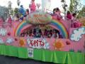 Desfile temático 'El Mundo de la Patata' con niños en un carro temático de color rosa y arcoíris, celebrando con alegría.