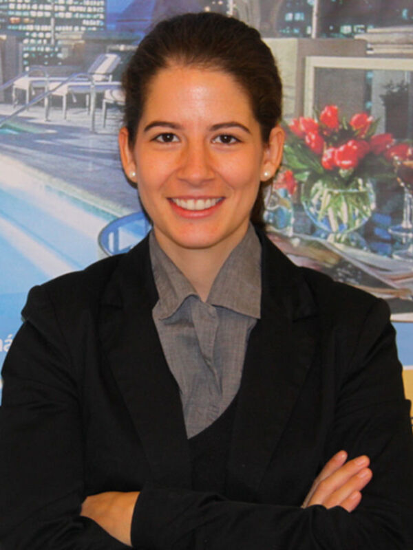 Profesora de negocios en la Universidad de Miami, con un fondo de piscina y flores rojas en el fondo.