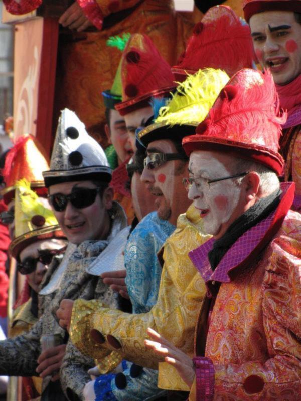 Personas disfrazadas con sombreros coloridos y disfraces brillantes en un desfile festivo.
