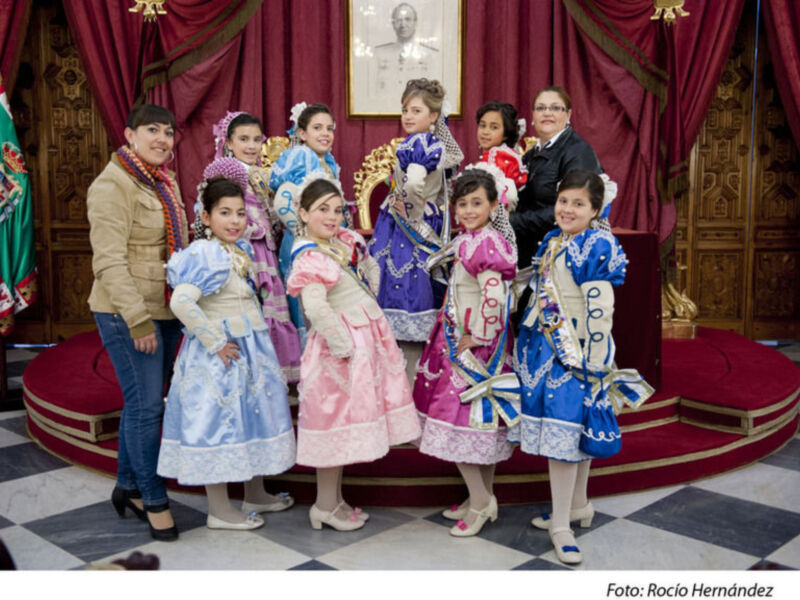 Niños vestidos con trajes tradicionales posando para una foto en un palacio.