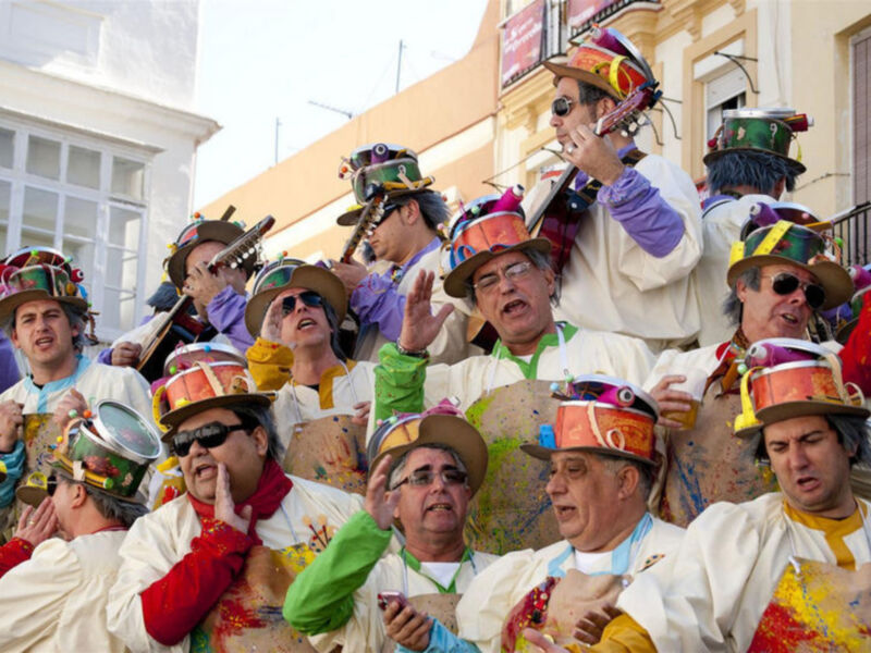 Un grupo de personas con sombreros coloridos y disfraces participando en una celebración festiva.