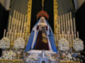 Altar con imagen de la Virgen de la Soledad, rodeada de velas y flores, en un entorno religioso.