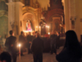 Una iglesia con altares dorados y velas encendidas, gente en uniforme se dirige hacia el altar.