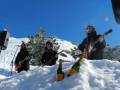 Tres músicos en la nieve con instrumentos y champán.