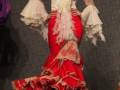 Modela desfilando con un vestido flamenca de color rojo y blanco, con detalles de encaje y volantes.