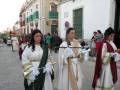 Personas vestidas con trajes tradicionales caminando por una calle.
