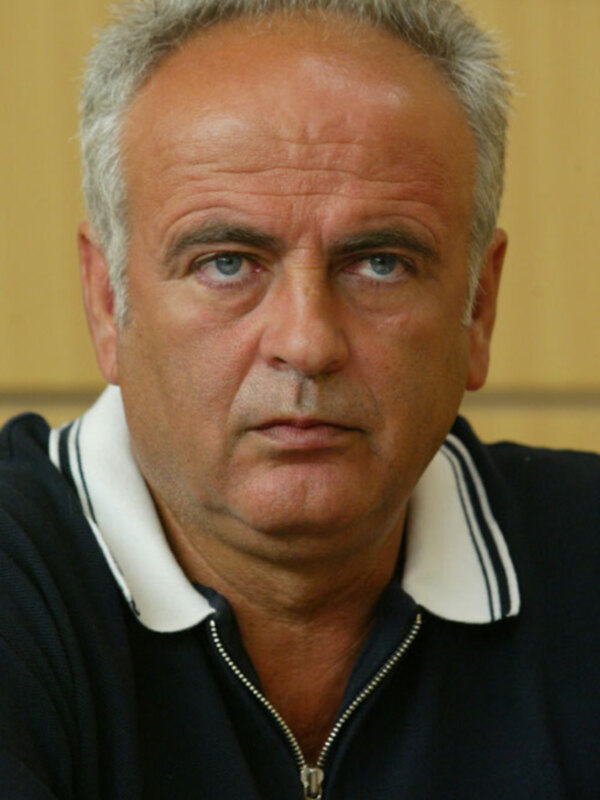 Un hombre con cabello gris y una camisa de cuello blanco y negro.