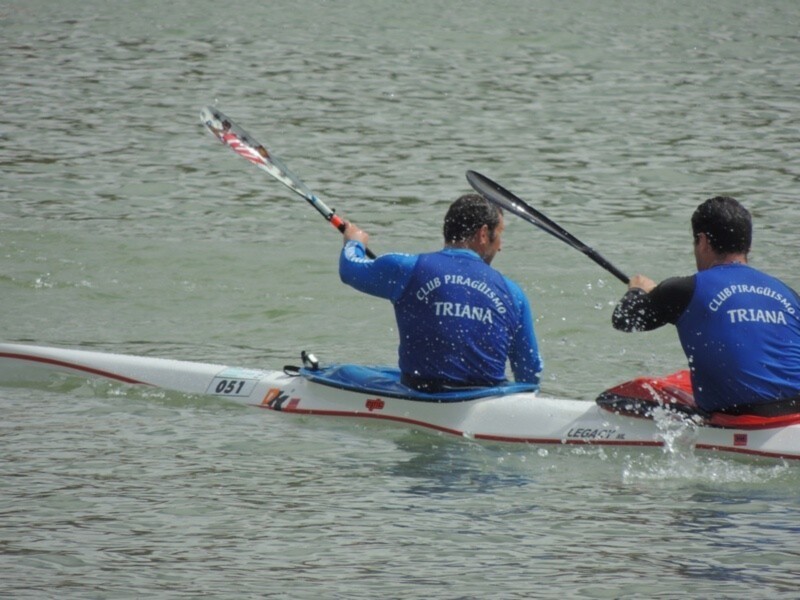 Dos personas en canoa en el agua, con el texto 'CLUB PIRAGÜISMO TRIANA' en sus chalecos.