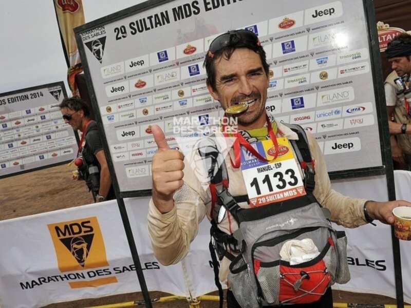 Manuel, un corredor de la carrera MDS, muestra su medalla de oro y el número 1133 en un evento deportivo.