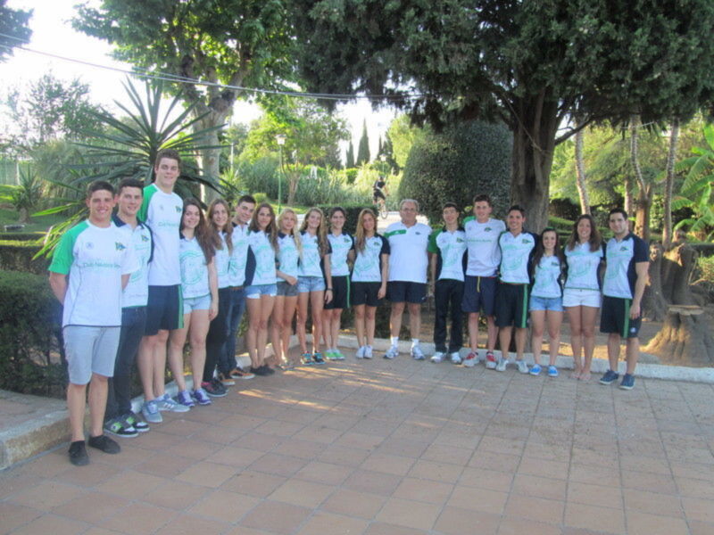 Equipo de jóvenes en camisetas verdes y blancas posando en un parque soleado.