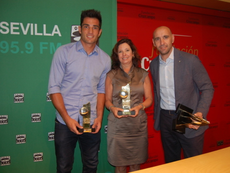 Tres personas posan con sus trofeos en un evento en Sevilla, patrocinado por Cruzcampo y 95.9 FM.