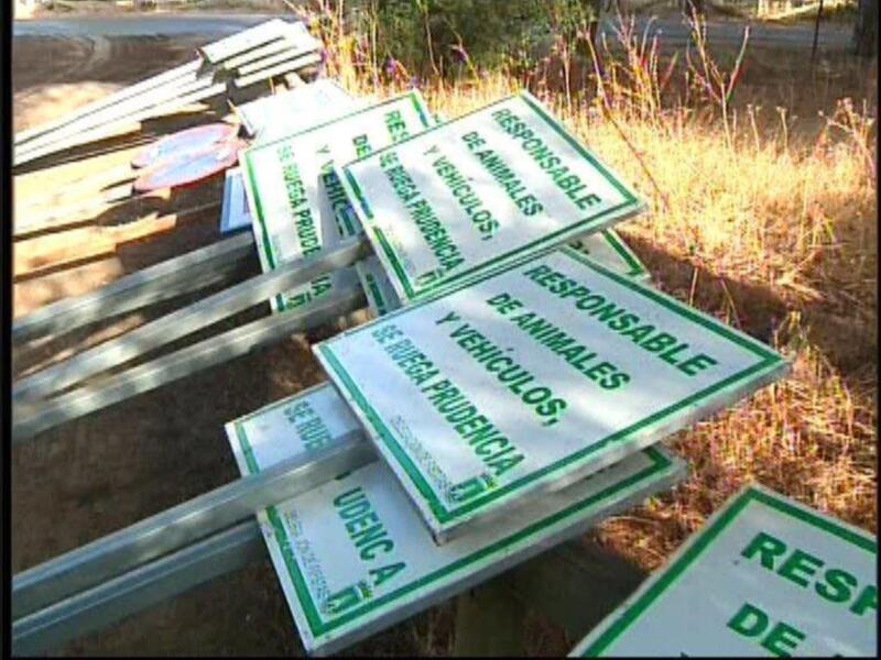 Señales de advertencia en español sobre responsabilidad de vehículos y animales en un camino rural.