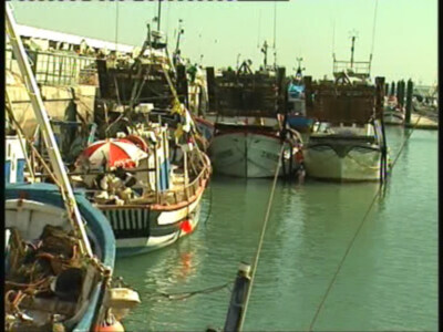 Barcos de pesca en un puerto, con una persona bajo el paraguas.