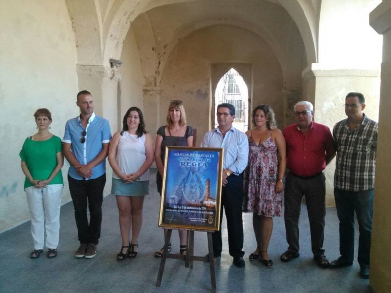 Una foto de grupo en una sala con arcos, con una persona sosteniendo un cartel informativo sobre 'Fiestas Aragonesas'.
