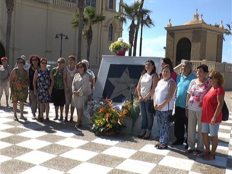 Un grupo de personas posa junto a una estrella de Hollywood en un entorno urbano con palmeras y edificios históricos al fondo.