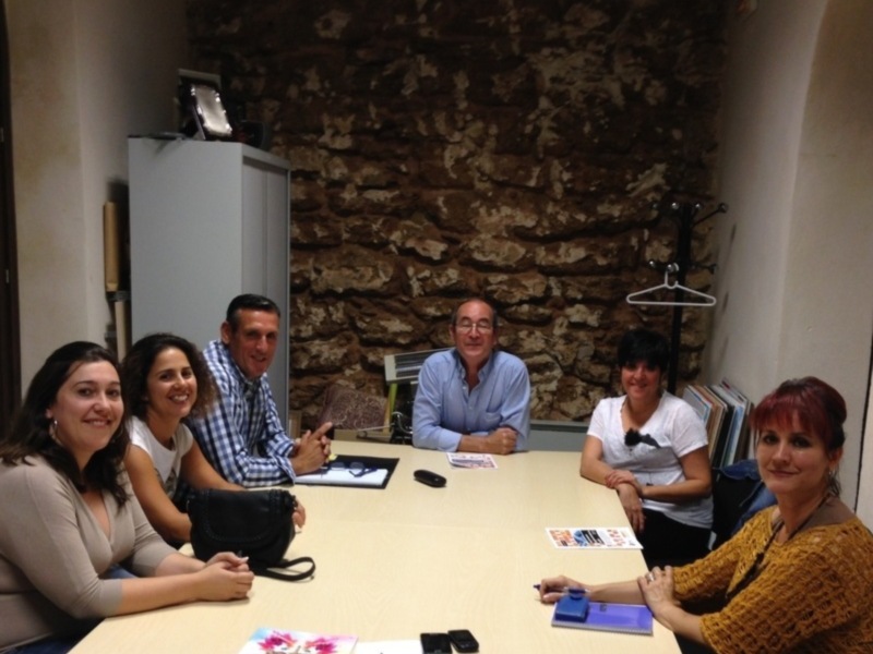Una reunión de trabajo en una oficina con personas sentadas en una mesa, con tarjetas y documentos en el centro.