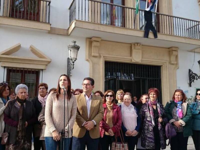 Conferencia pública en un edificio histórico, con una mujer hablando al micrófono y un grupo de personas escuchando.