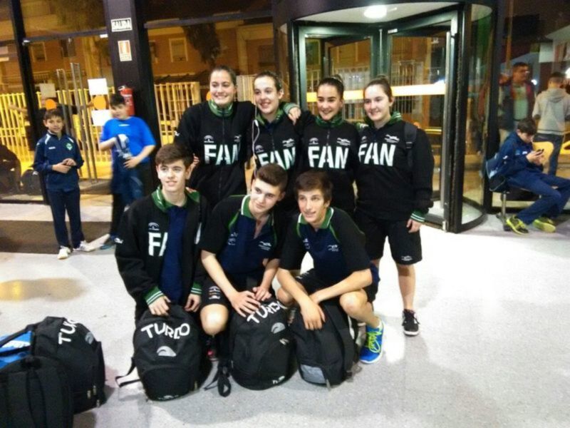 Un grupo de jóvenes deportistas posando con sus mochilas en una entrada de edificio, posiblemente antes de un entrenamiento o competición.