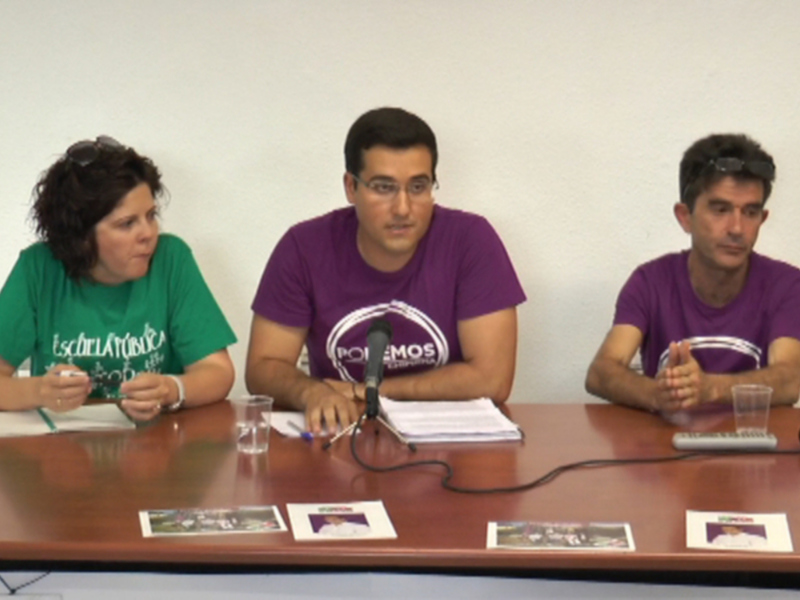 Tres personas sentadas en una mesa, con documentos y un micrófono.