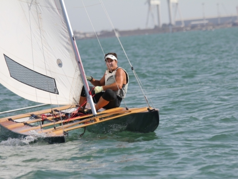 Hombre navegando en una embarcación de vela en el mar, con el casco y el casco de la vela visible.